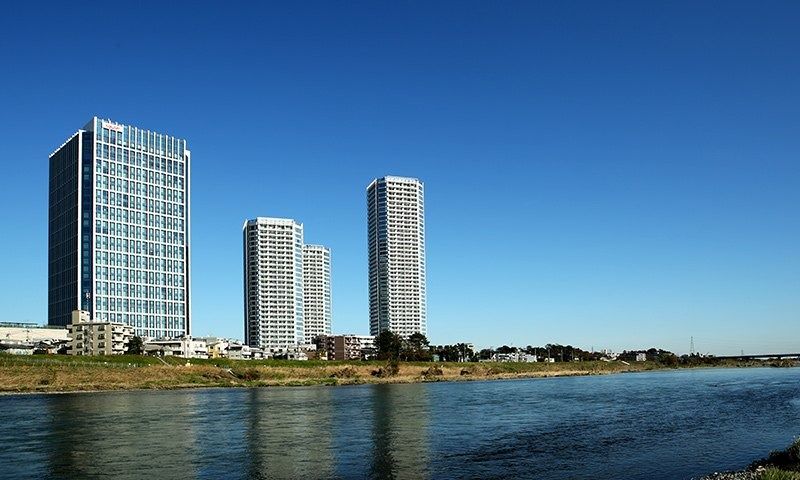 Rakuten Group: Riverside view of several towers under a clear sky
