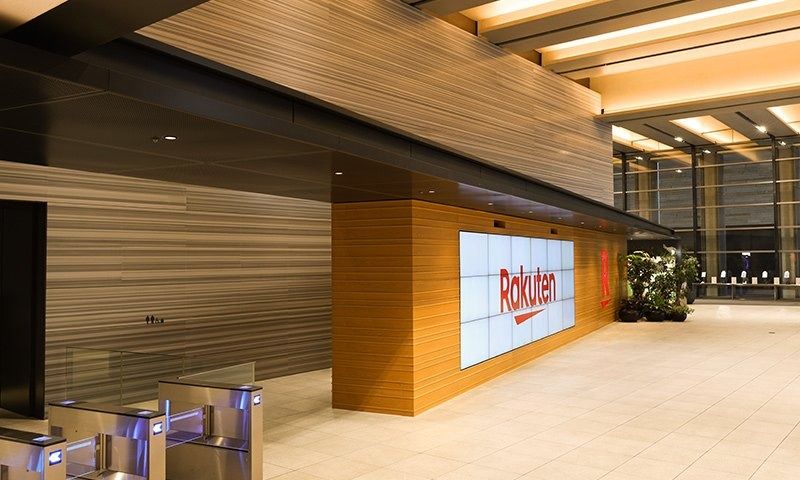 Rakuten Group: Security gates in front of a wood-panelled wall with a Rakuten screen