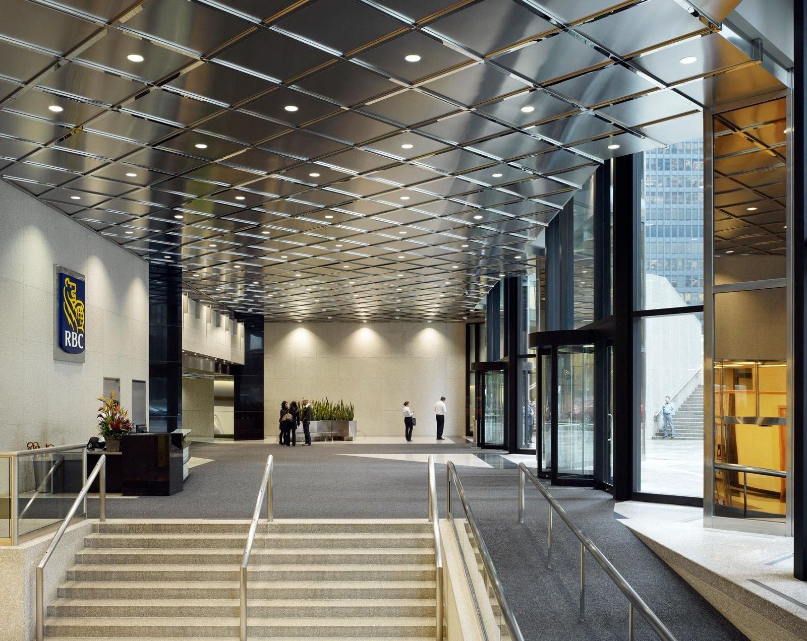 RBC (Royal Bank of Canada): Bright office lobby with stone steps, a metal ceiling grid and tall glass doors