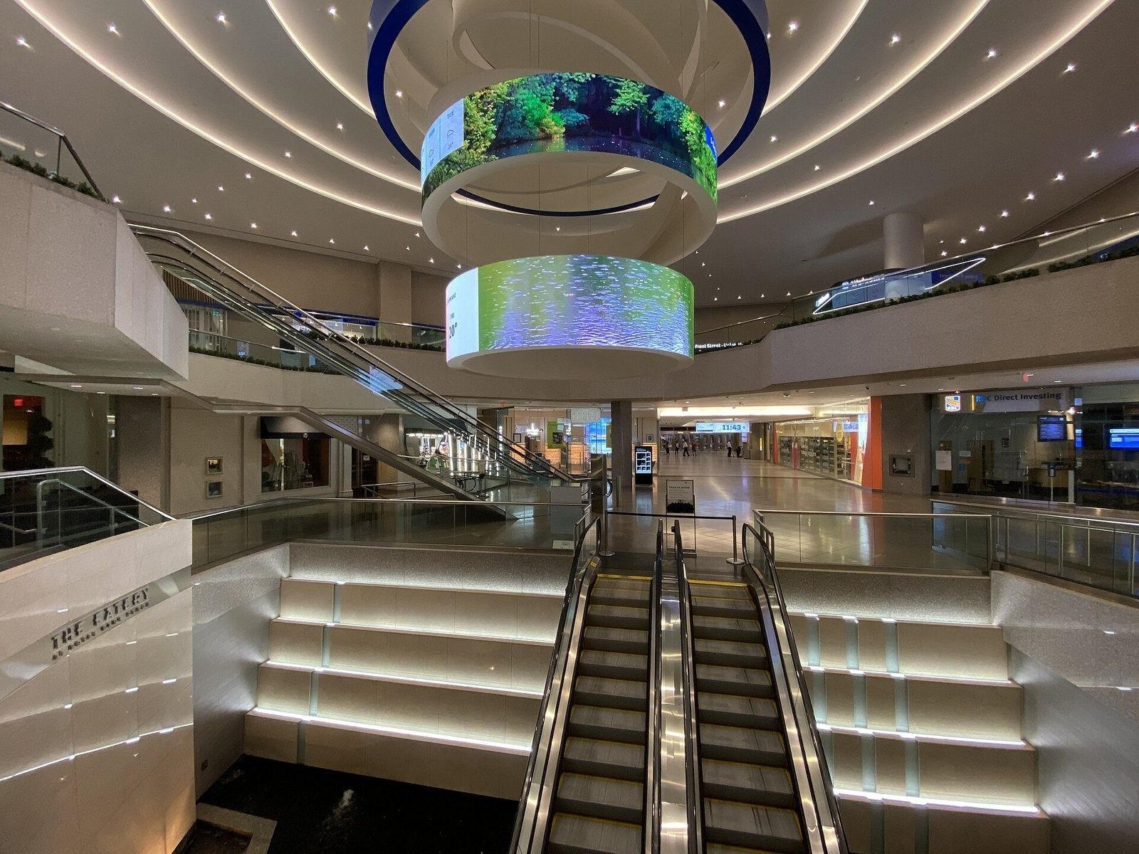 RBC (Royal Bank of Canada): Escalators descending beside illuminated steps under a circular digital screen