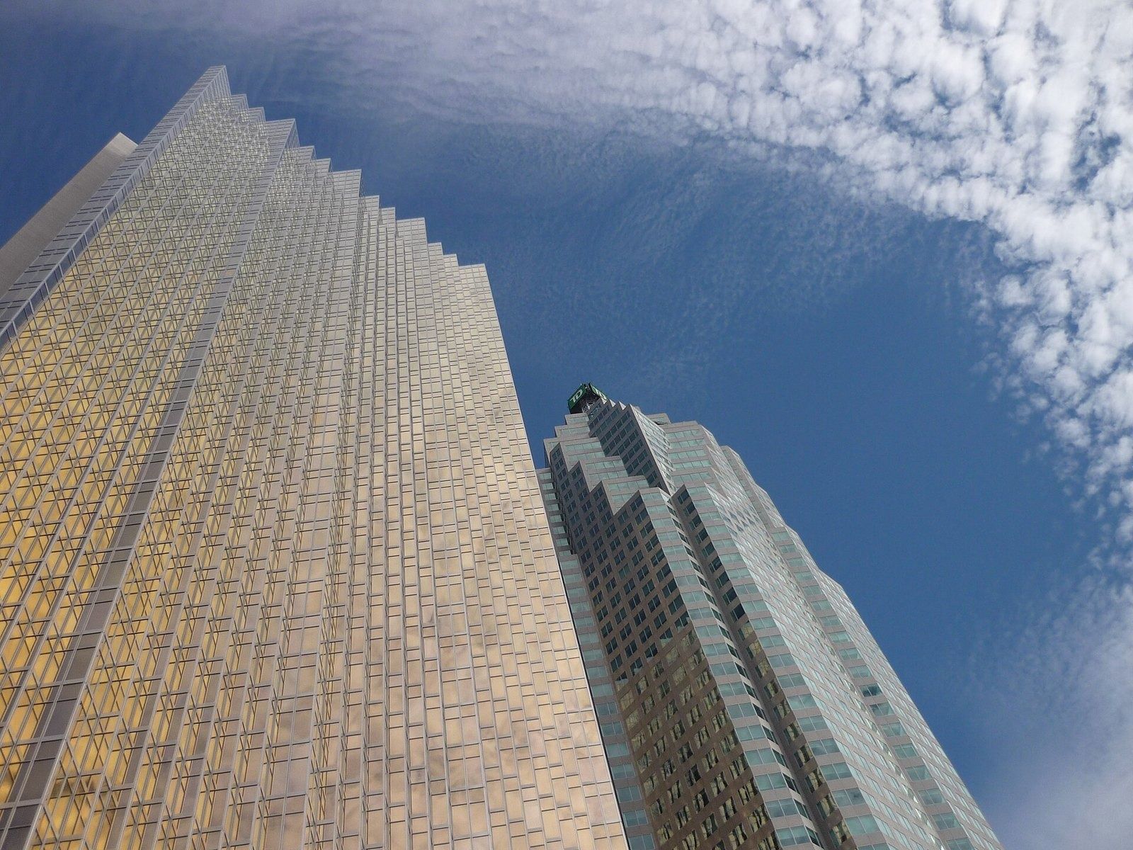 RBC (Royal Bank of Canada): Gold glass facade seen from below beside a blue-green tower