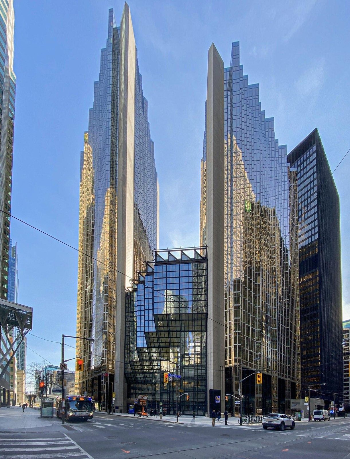 RBC (Royal Bank of Canada): Two tall gold glass towers with sawtooth facades and a lower glass atrium between them under blue sky