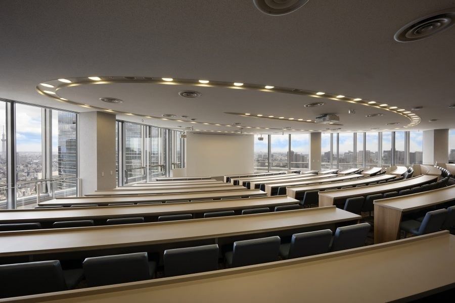 Recruit Holdings: Curved rows of desks in a hall with a ring of ceiling lights
