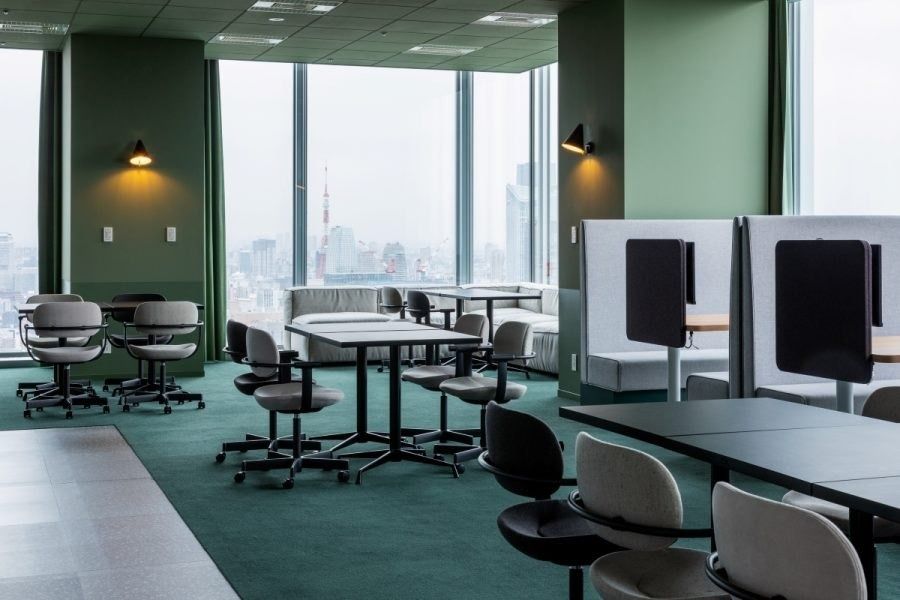 Recruit Holdings: Green-walled area with round tables and booth seats by the window