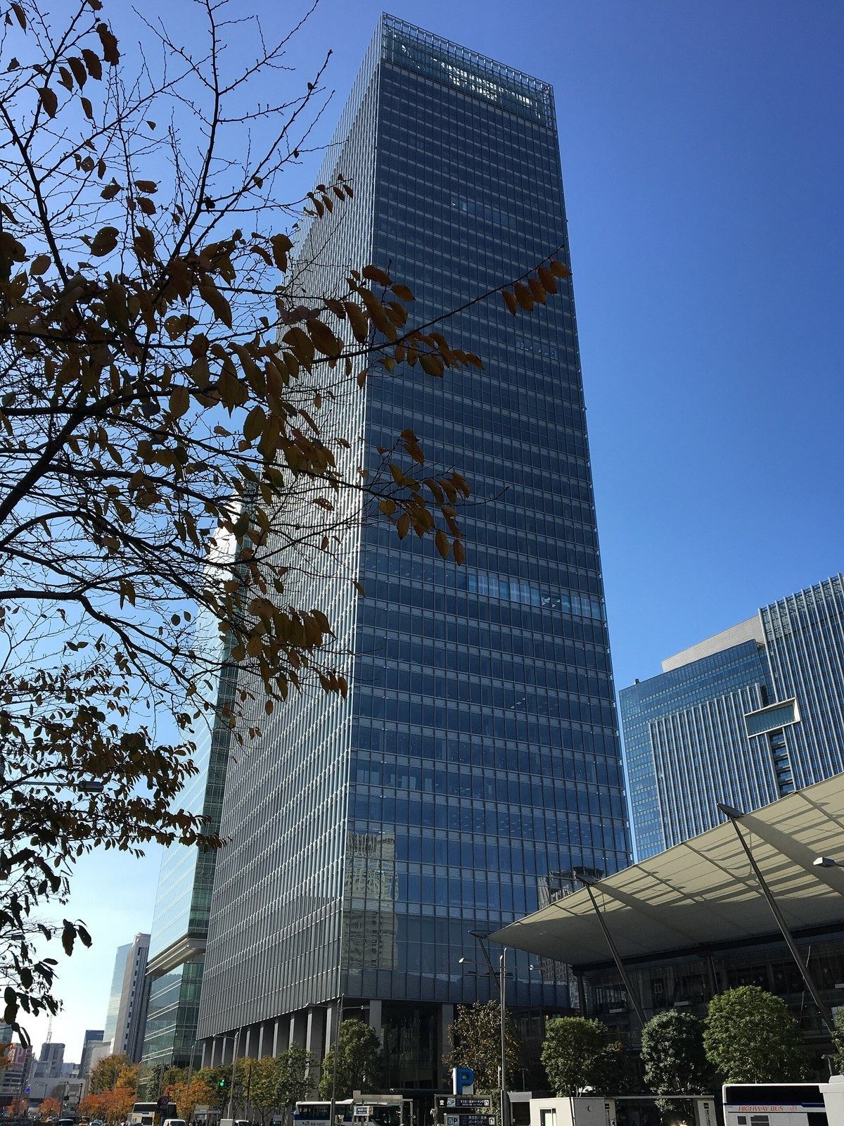 Recruit Holdings: Tall glass tower behind bare trees