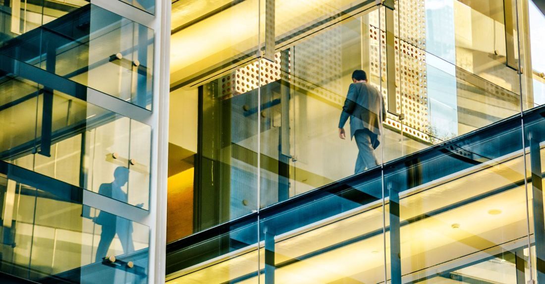 Repsol: A person seen from behind crossing a glass walkway lit in warm tones