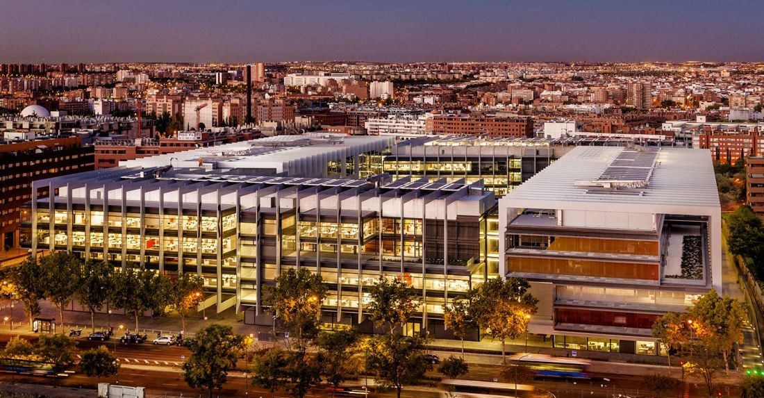 Repsol: Aerial view of the lit campus at dusk with the city behind