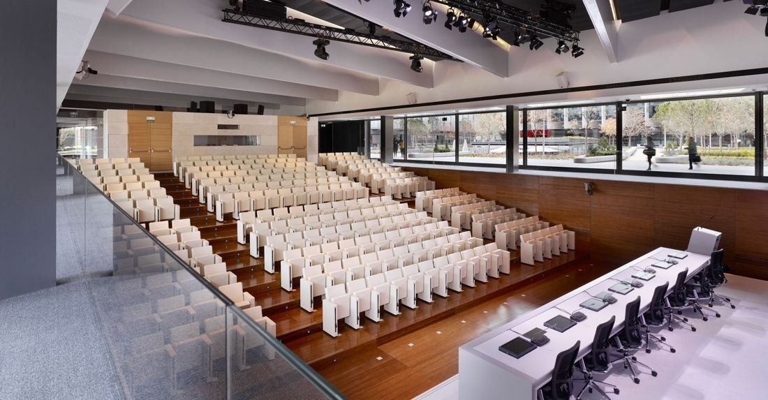 Repsol: Auditorium with rows of white seats, a stage table and a long window