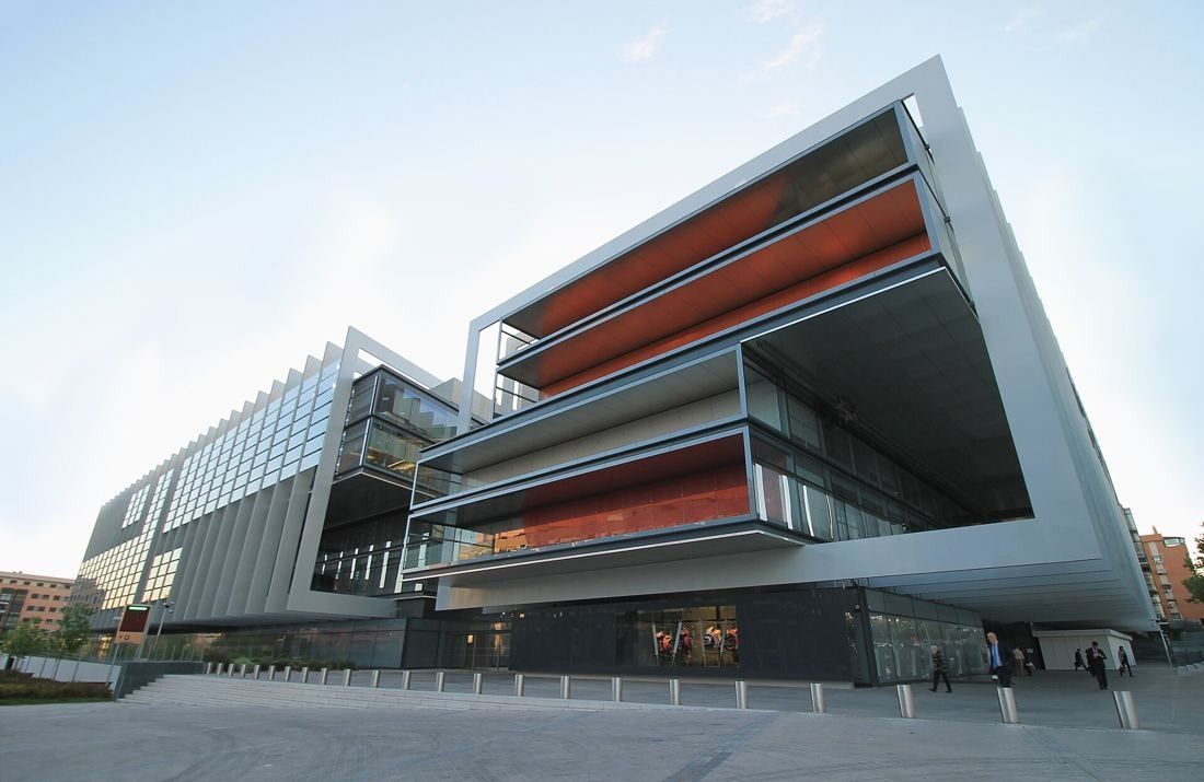 Repsol: Corner of the building with cantilevered glass floors lined in orange, seen from the street