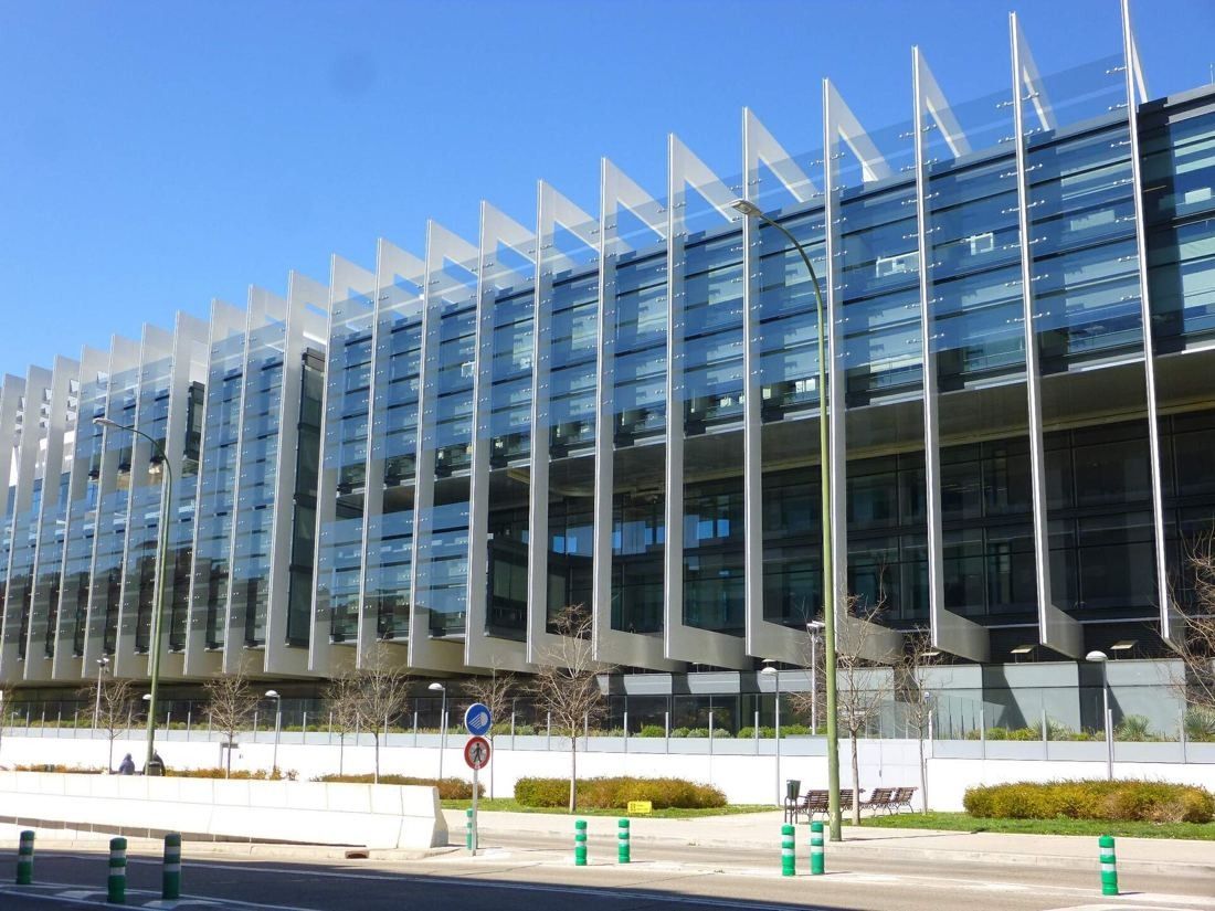 Repsol: Long glass façade behind slim white fins on a sunny day