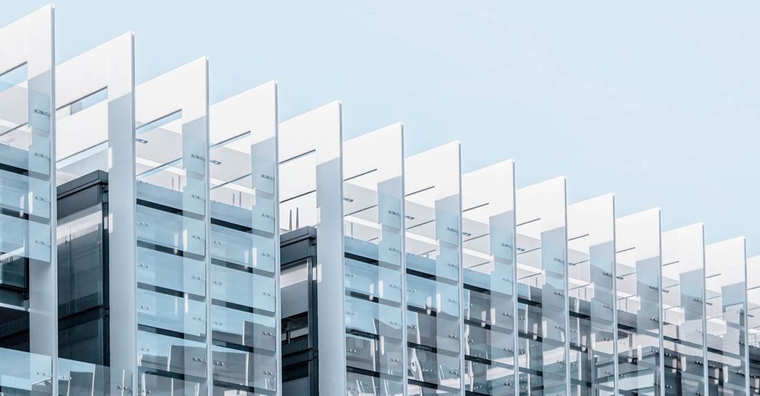 Repsol: Row of white angled fins in front of glass floors against a pale sky