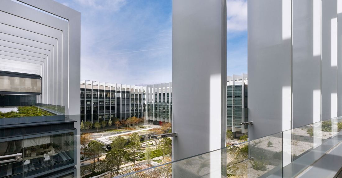 Repsol: View past white fins across the garden toward other glass buildings of the campus