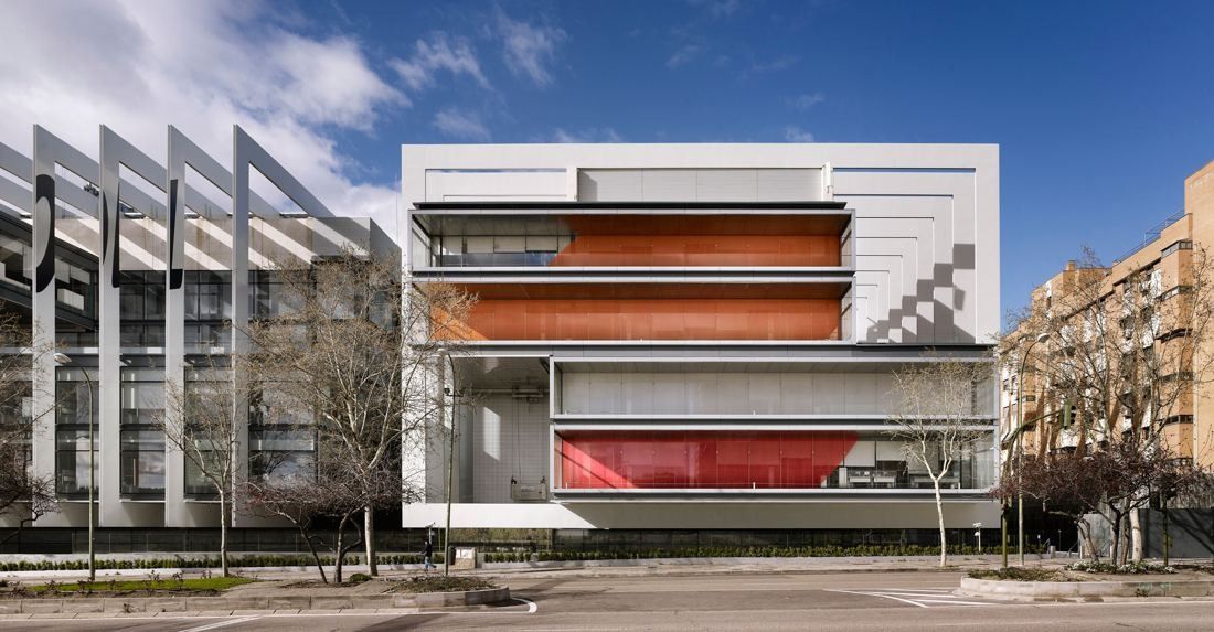 Repsol: White-framed building with orange-lined glass floors next to a finned façade, seen from the street