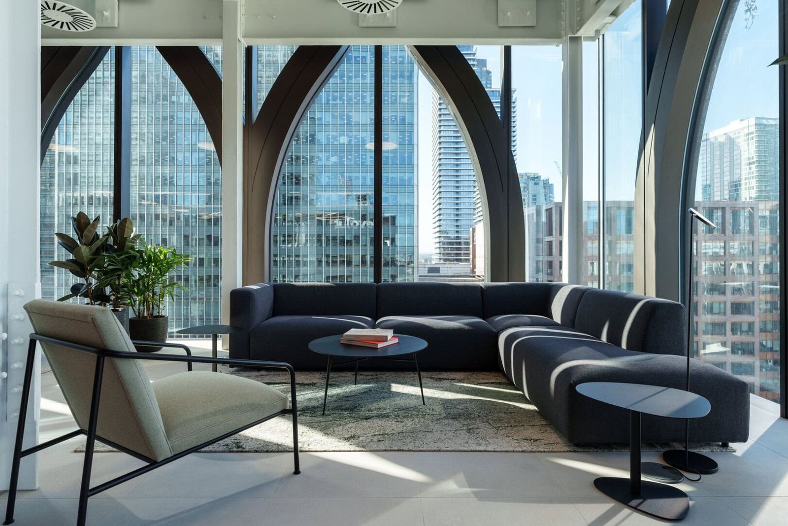 Revolut: Lounge sofas in front of tall arched window frames over Canary Wharf