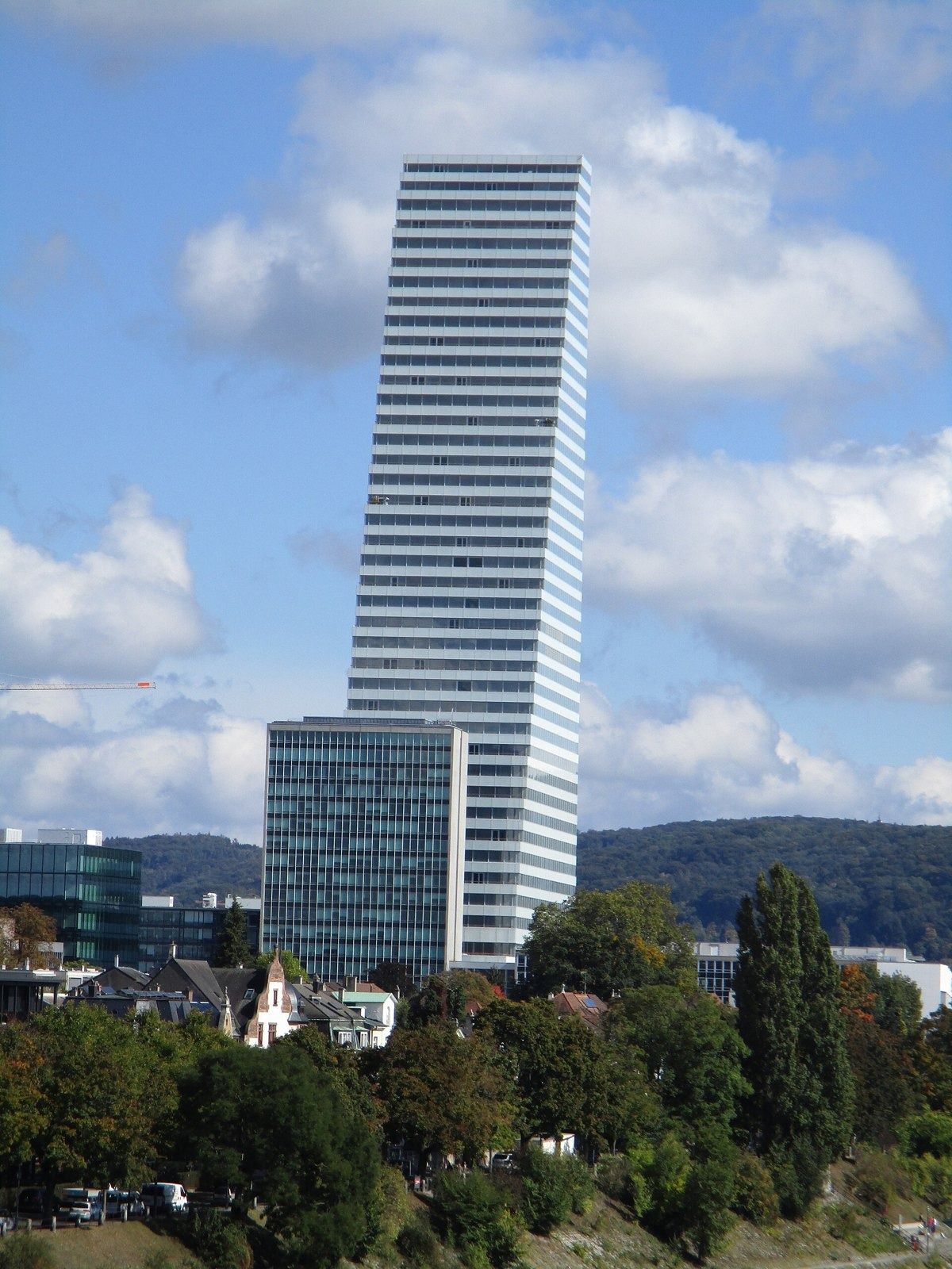 A single stepped white tower above trees by the Rhine
