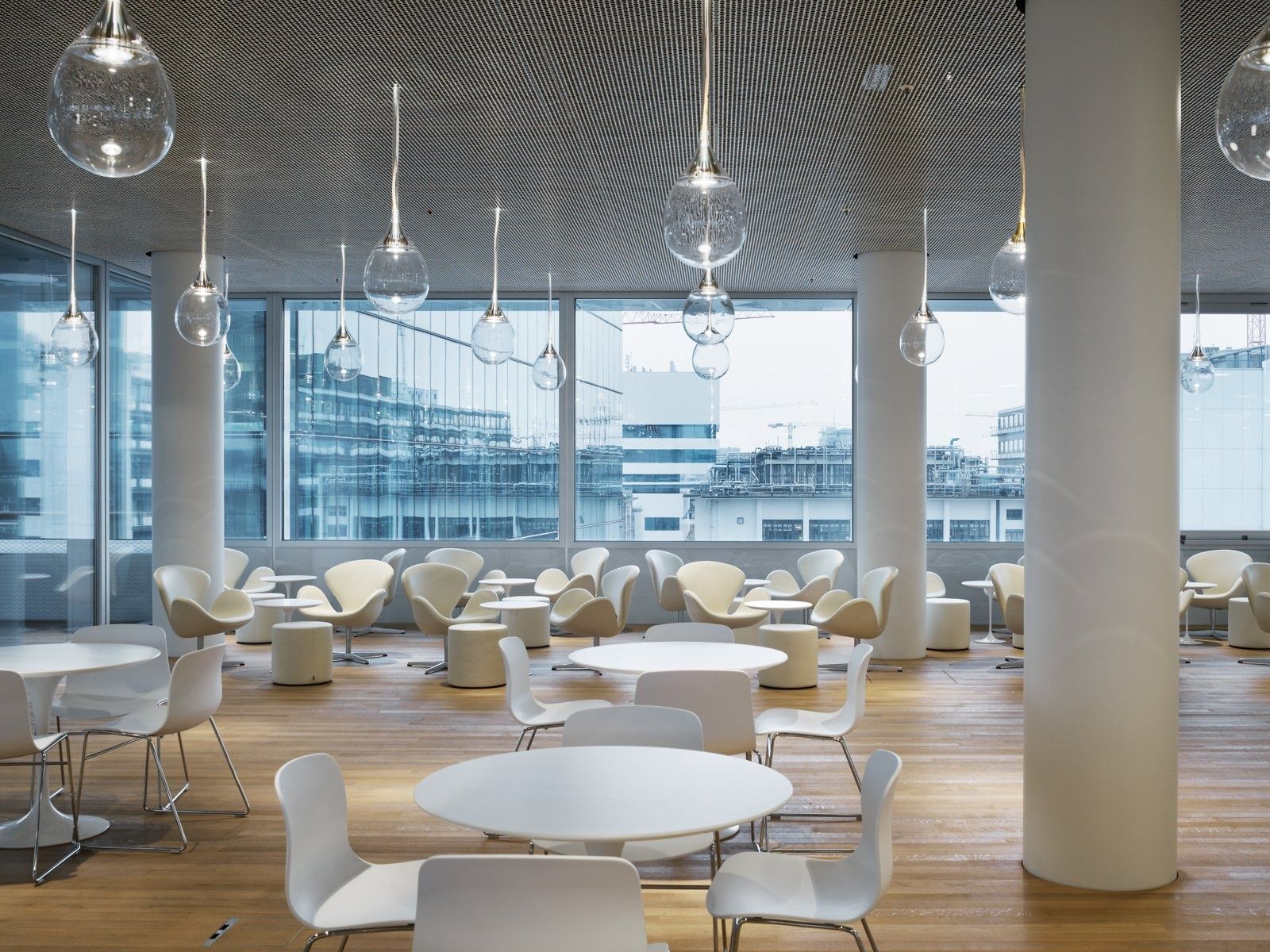 Roche: Café tables under glass pendant lamps by a window wall