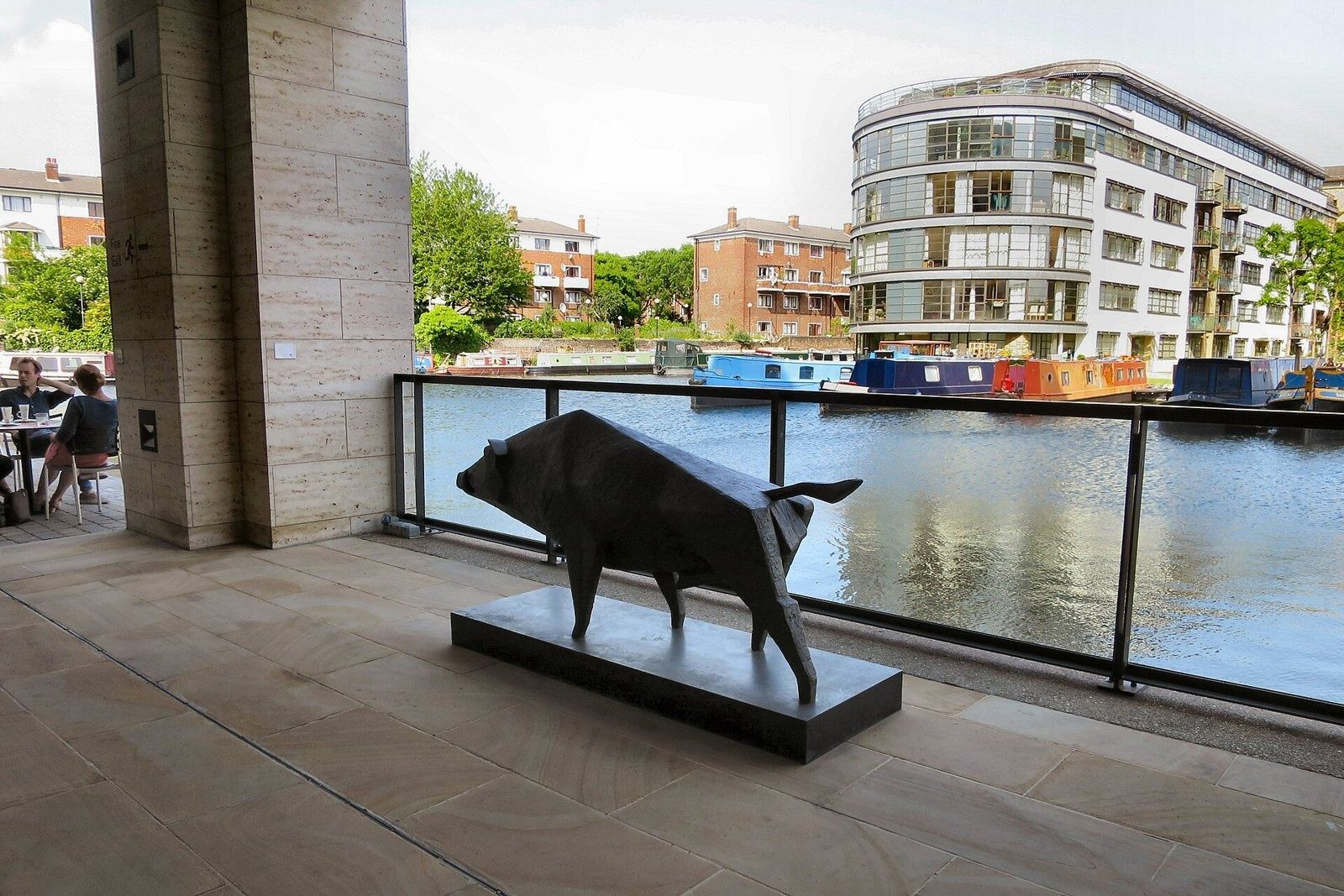 Rolls-Royce: Bronze boar sculpture on a terrace overlooking a canal basin with moored boats