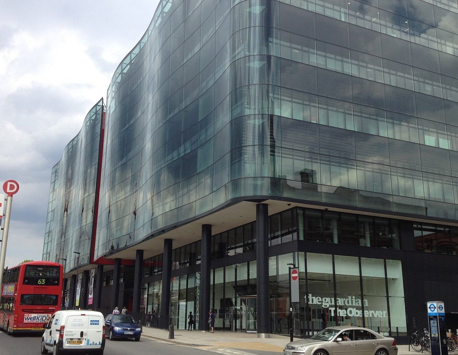 Rolls-Royce: Corner of a glass office building at street level with a red bus passing