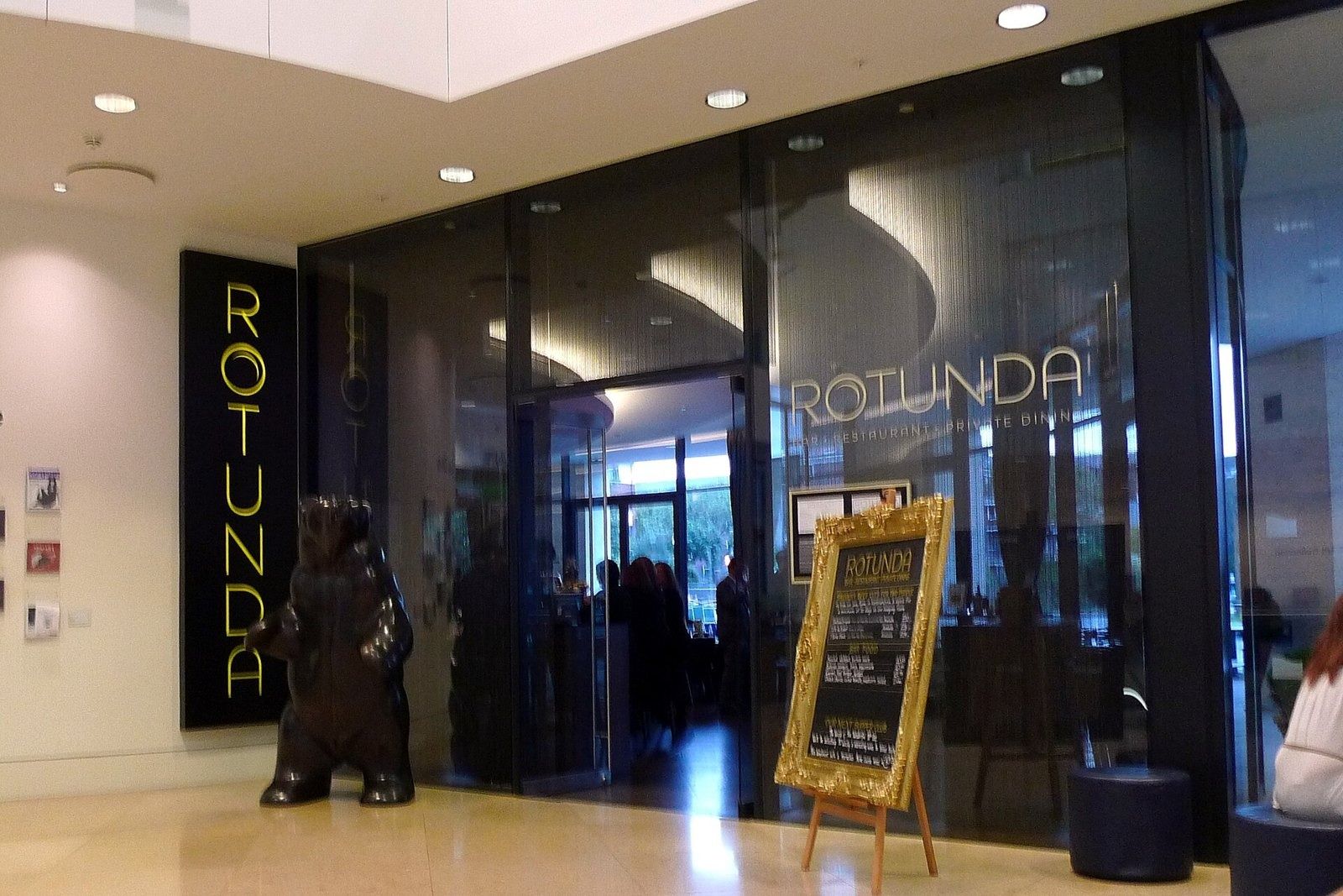 Rolls-Royce: Glass entrance to a bar and restaurant signed Rotunda, with a bear sculpture outside