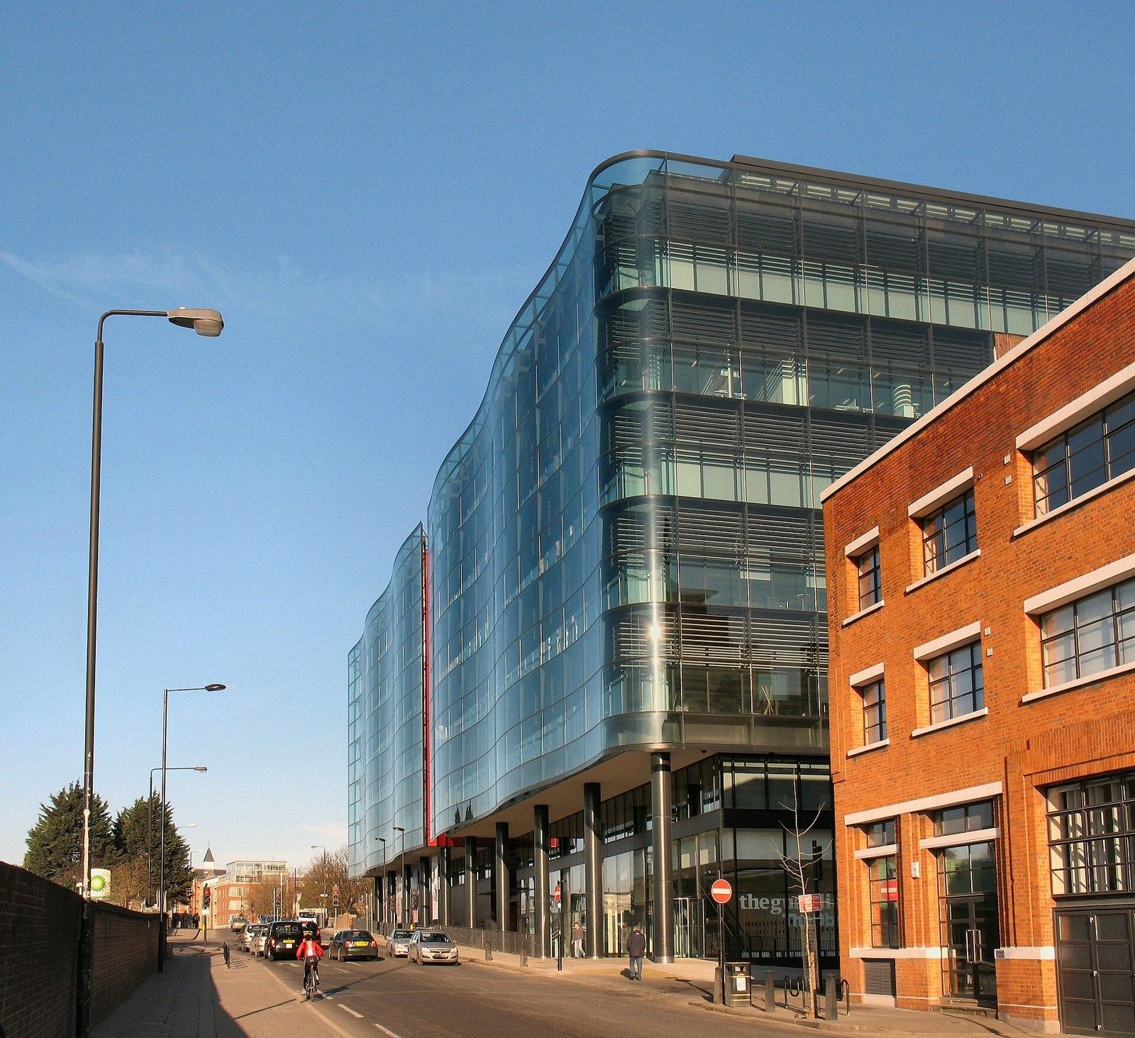 Rolls-Royce: Street view of a curved glass office building beside a red-brick building
