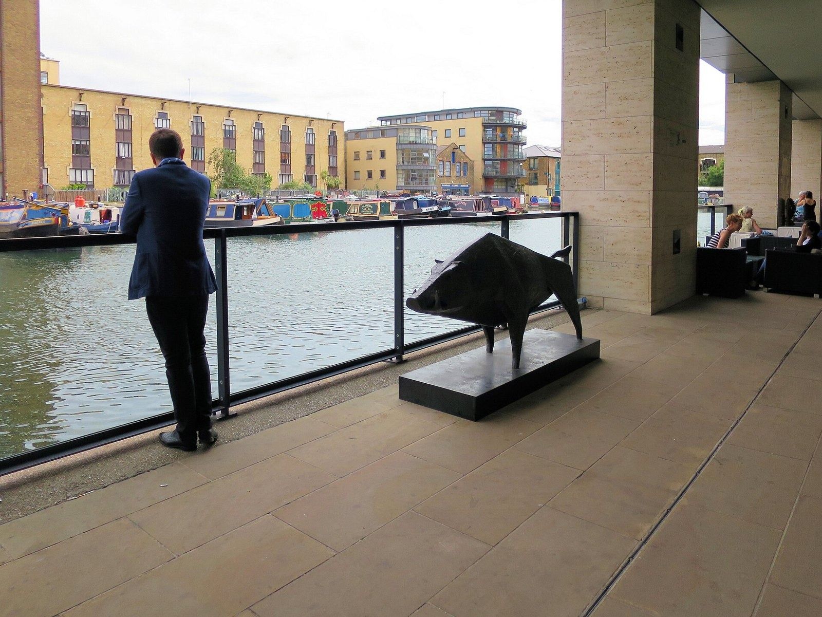 Rolls-Royce: Waterside terrace with a boar sculpture and a person seen from behind looking over the basin
