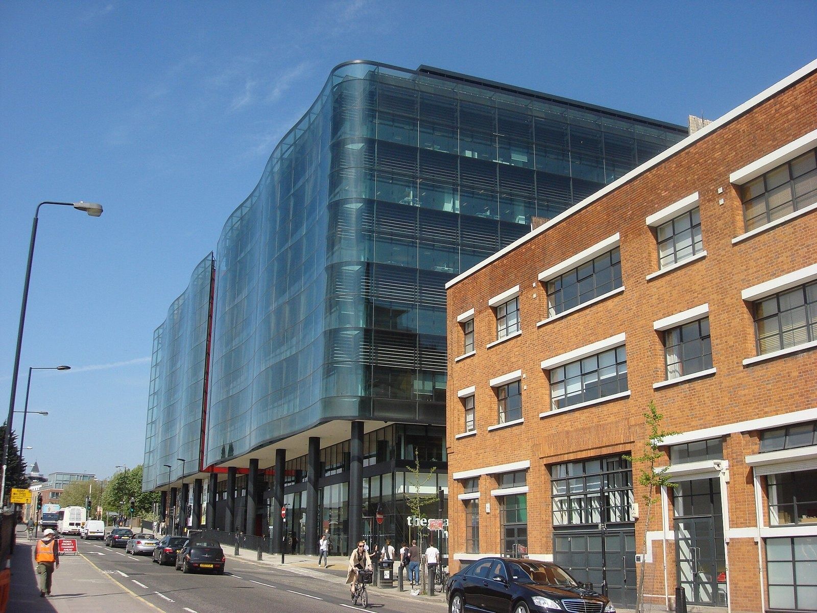 Rolls-Royce: Wavy glass façade of an office building along a street, next to a brick warehouse