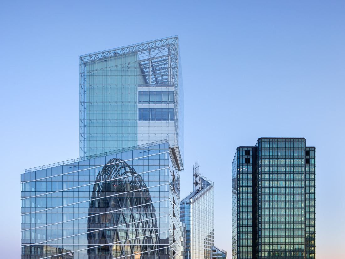 Saint-Gobain: Glass tower with an offset crown rising behind an egg-shaped tower under a blue sky