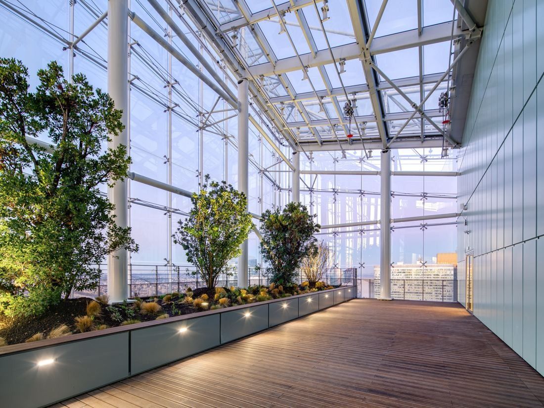 Saint-Gobain: Indoor garden with trees in planters and a wooden deck under a glass roof