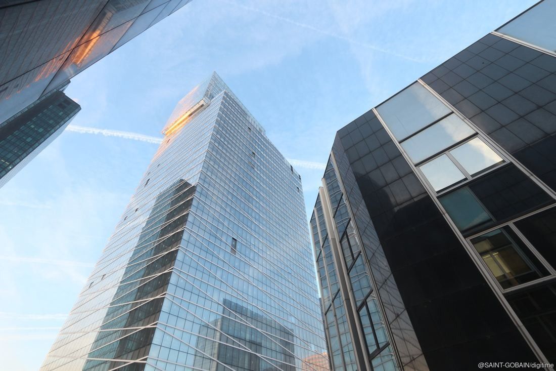 Saint-Gobain: Looking up at a sharp-edged glass tower between other high-rises