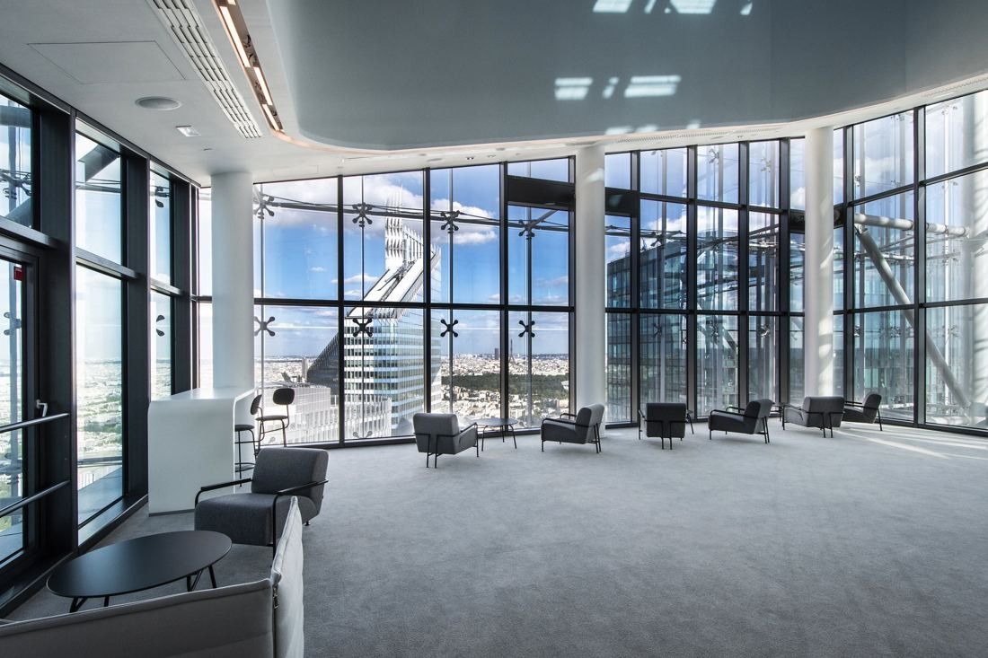 Saint-Gobain: Lounge chairs and tables beside floor-to-ceiling windows overlooking La Défense