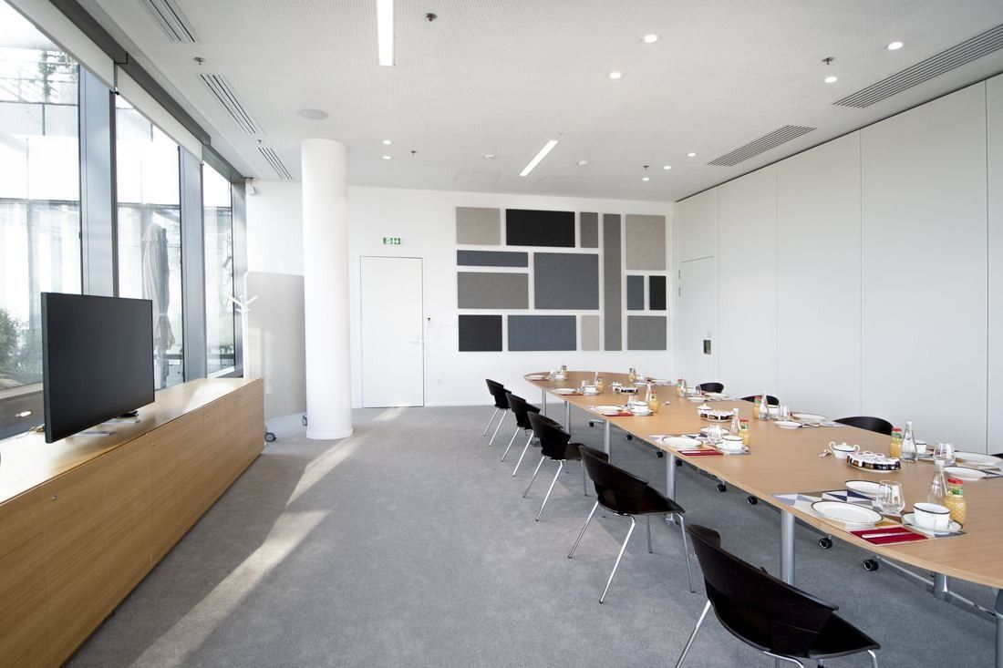Saint-Gobain: Meeting room with a long wooden table, black chairs and a wall screen
