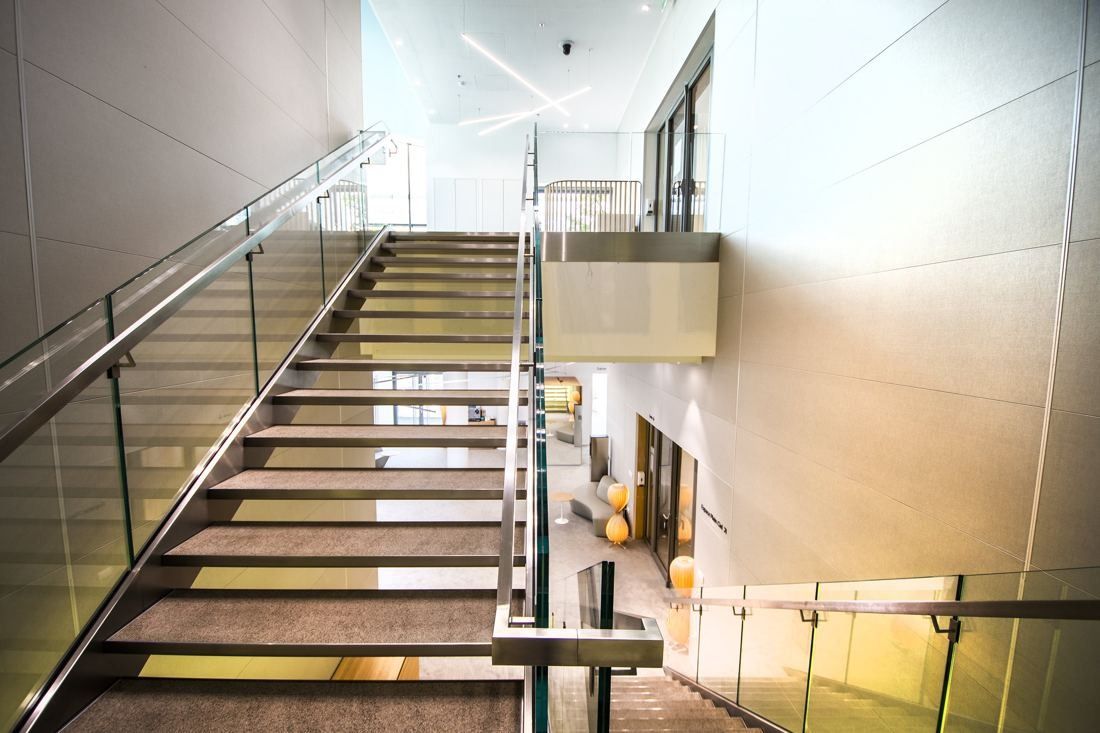 Saint-Gobain: Open staircase with glass railings in a bright double-height space