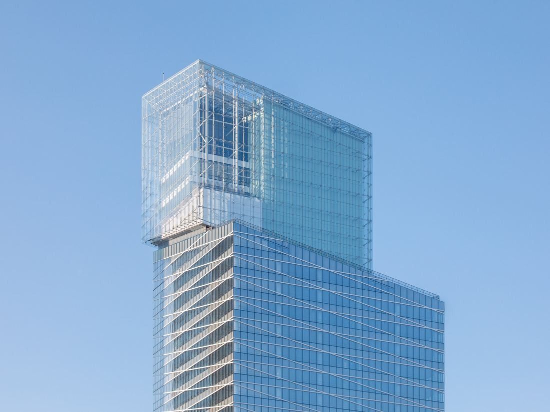 Saint-Gobain: Upper part of a glass tower with a stepped, see-through crown against a pale blue sky