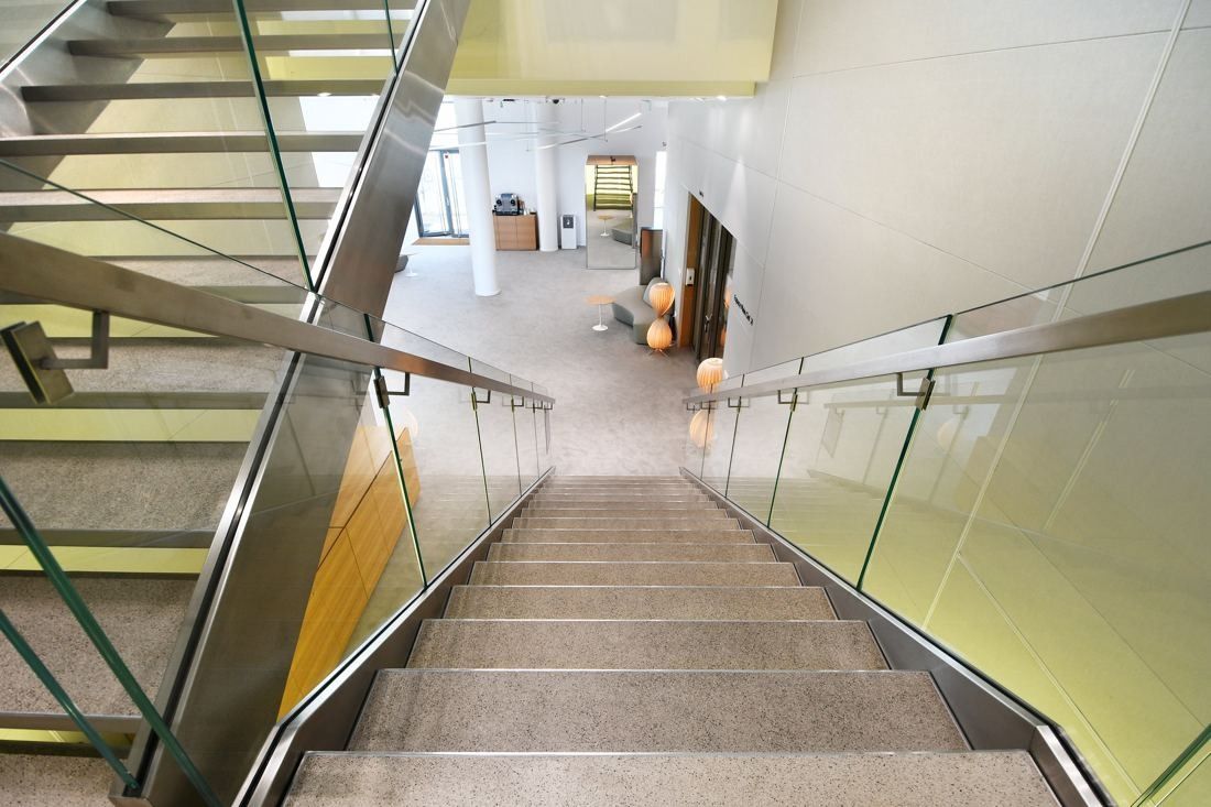 Saint-Gobain: Wide staircase with glass balustrades leading down to an open floor