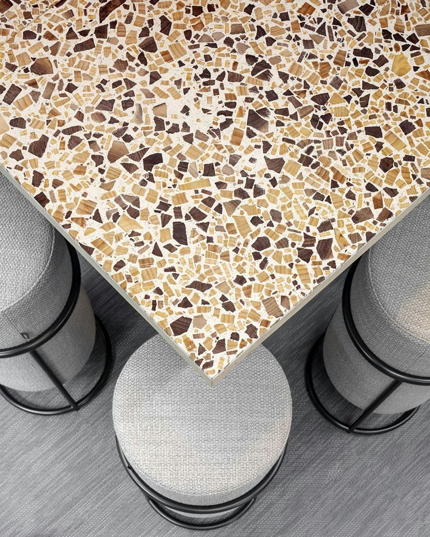 Sanofi: Close-up of a speckled terrazzo counter corner above upholstered stools