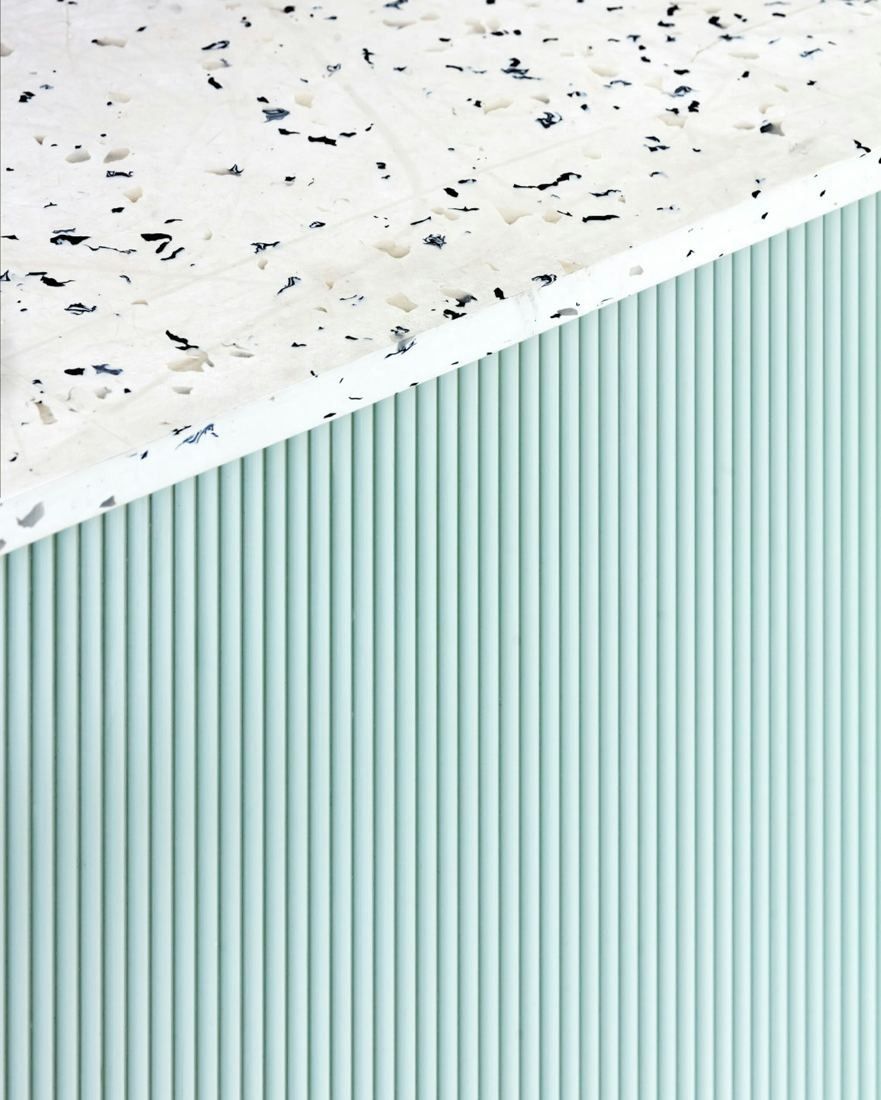 Sanofi: Close-up of a white speckled terrazzo top over pale green fluted panelling