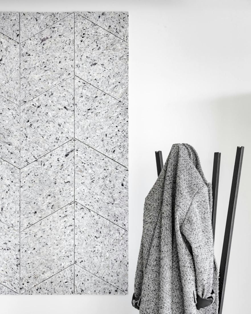 Sanofi: Speckled grey acoustic wall panel beside a black coat stand holding a coat