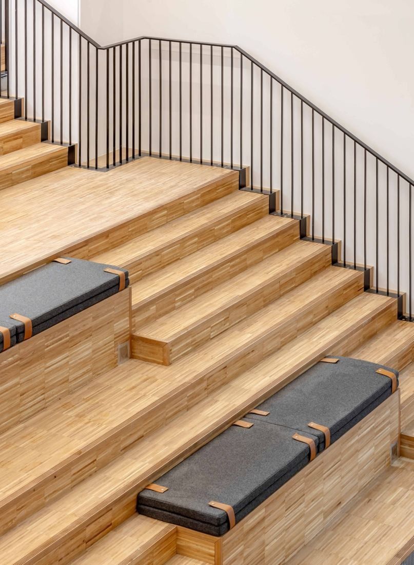 Sanofi: Wooden steps with cushions and a black metal handrail against a white wall