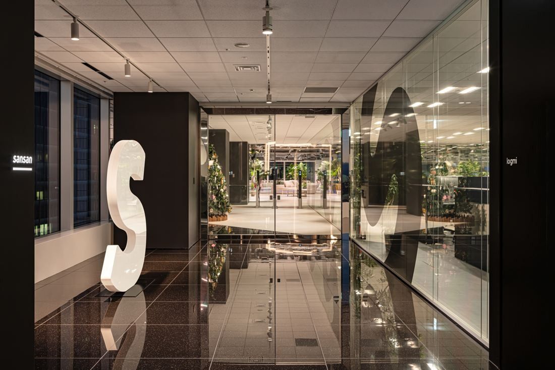 Sansan: Dark entrance corridor with a large white S sculpture and glass doors