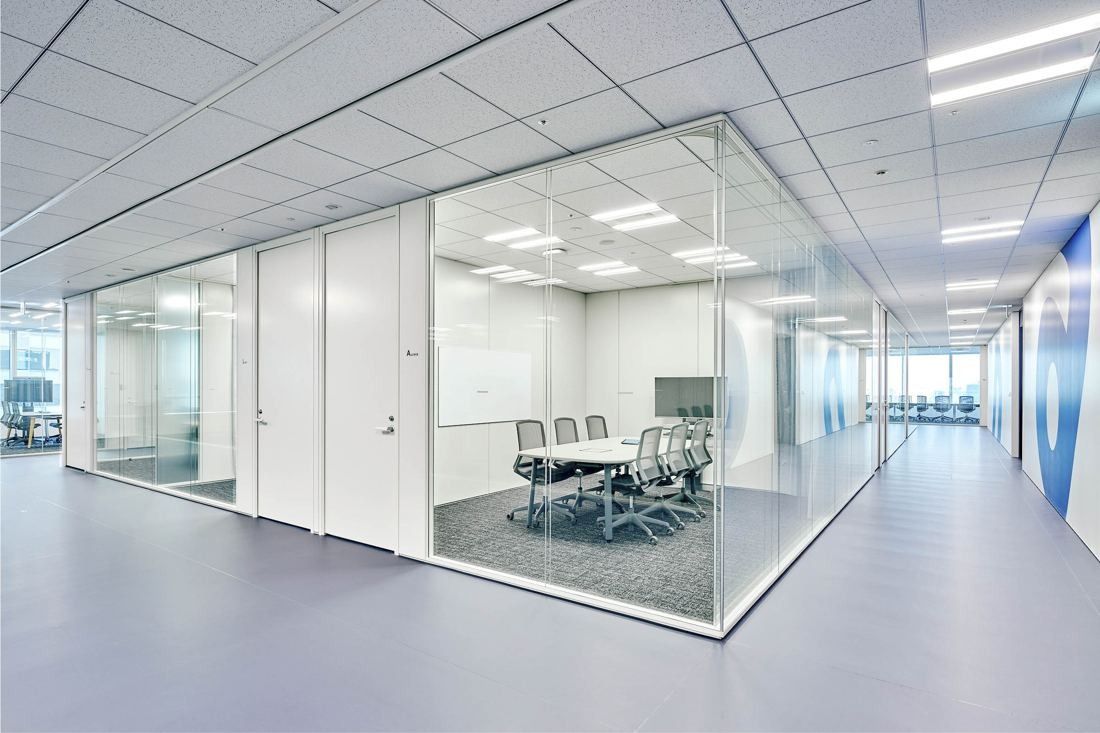 Sansan: Glass-walled meeting rooms along a bright corridor