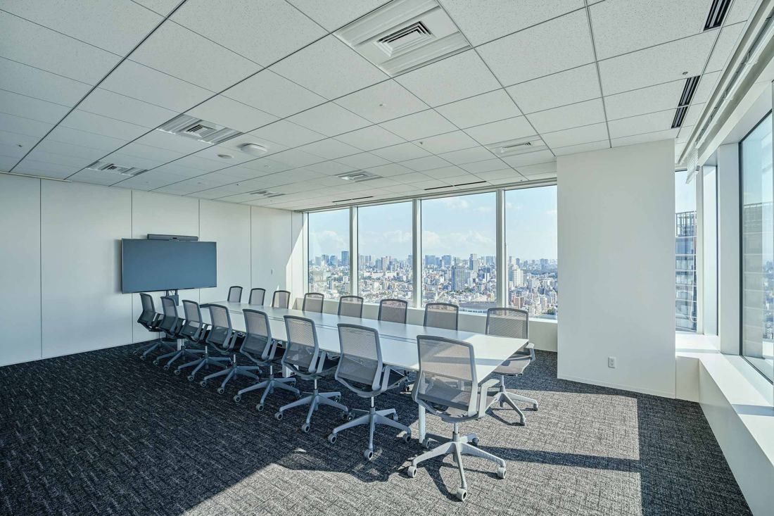 Sansan: Large meeting room with a long table, mesh chairs and a screen