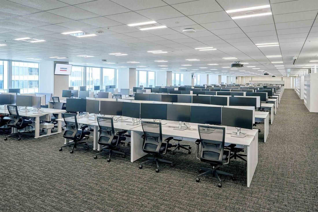 Sansan: Long rows of desks with monitors on a carpeted office floor