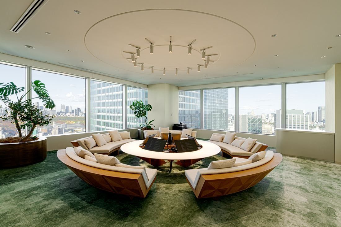 Sansan: Round sunken seating with a circular table under a ring-shaped light, green carpet and city views