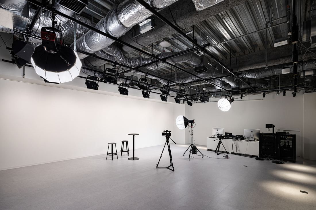 Sansan: Studio with a white cyclorama wall, lights and a camera on a tripod