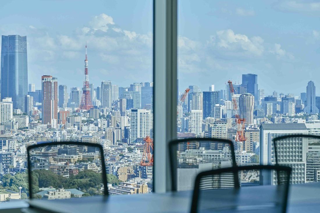 Sansan: View of central Tokyo with Tokyo Tower beyond office chairs and a window