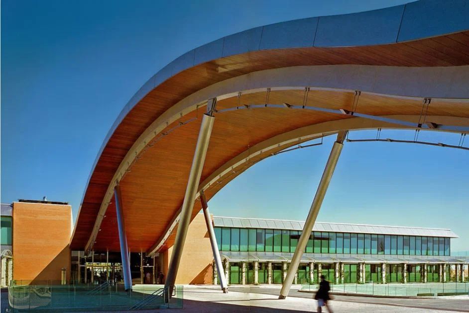 Banco Santander: Wide curved timber roof on slender steel supports over a glass-fronted building
