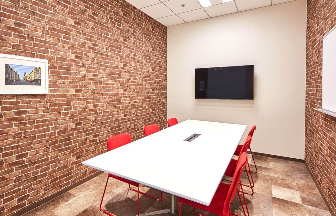 SEGA: Meeting room with a red brick wall, white table and red chairs