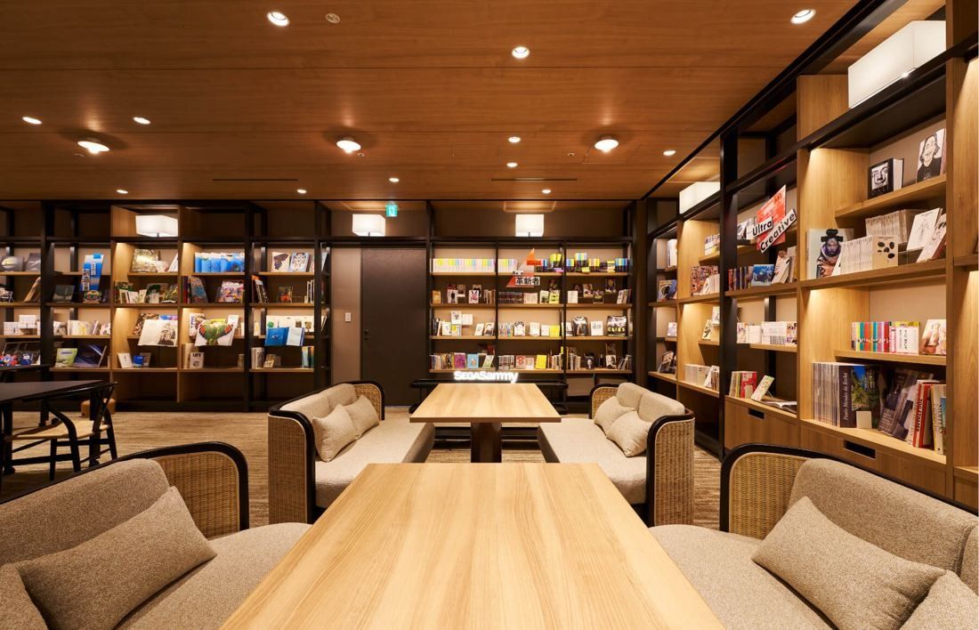 SEGA: Reading area with a wooden table, armchairs and floor-to-ceiling bookshelves