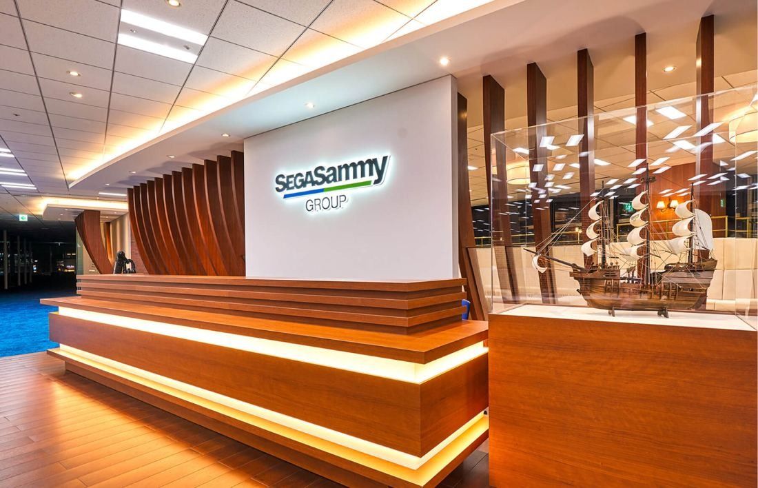 SEGA: Reception counter with warm lighting and a model sailing ship in a glass case