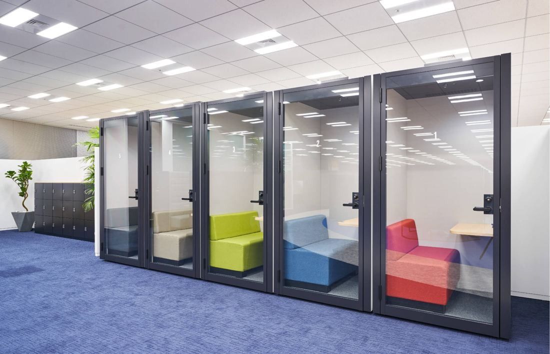 SEGA: Row of glass phone booths with colorful sofas inside